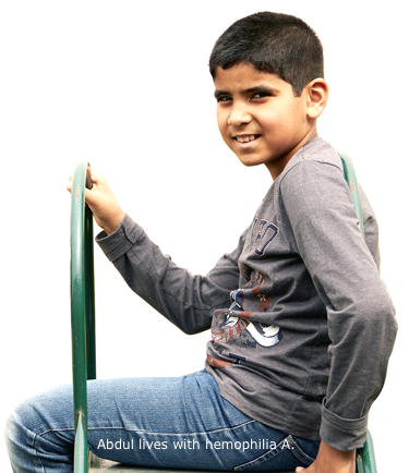 Profile view of Abdul, who lives with hemophilia A, sitting at the top of a slide, smiling and turned toward camera
