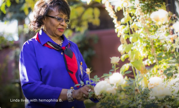 Linda, who lives with hemophilia B Linda, who lives with hemophilia B, standing in a flower garden and looking at a rose